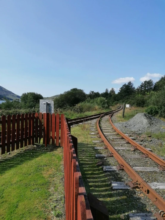 a railway track next to a lush green field