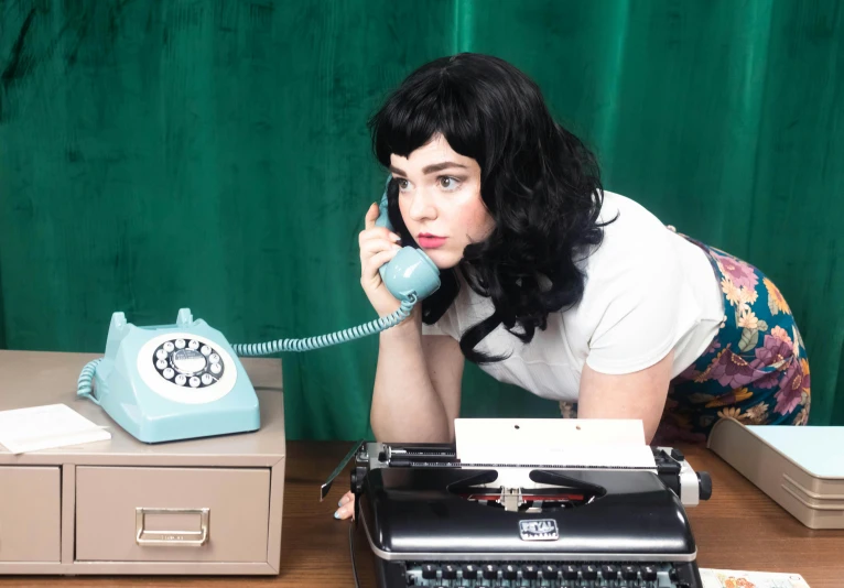 there is a woman on the phone next to an old typewriter