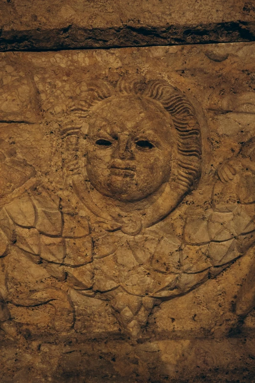 a decorative face is carved into the side of a stone wall