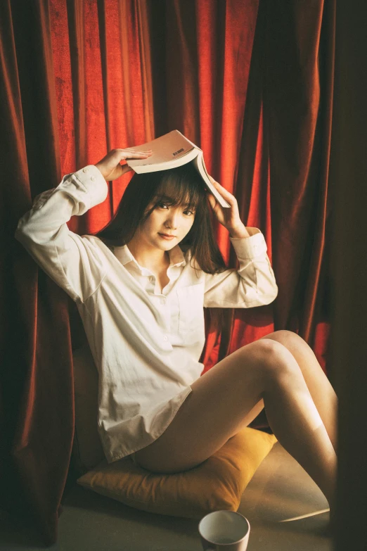 a girl sitting on the floor with a book in her hair