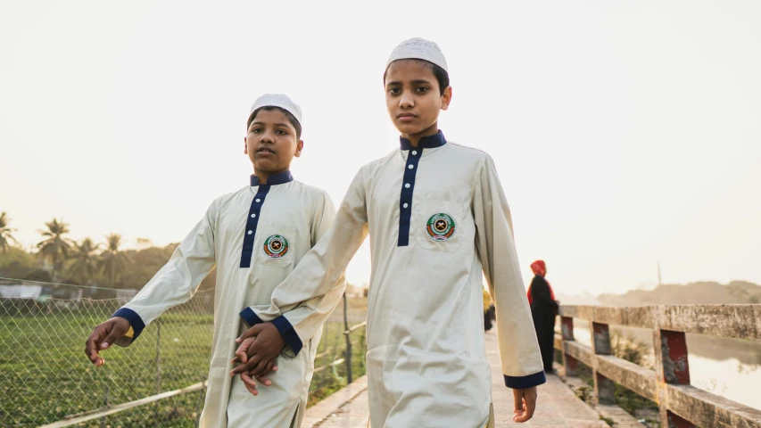 two boys walking along the shore of a body of water