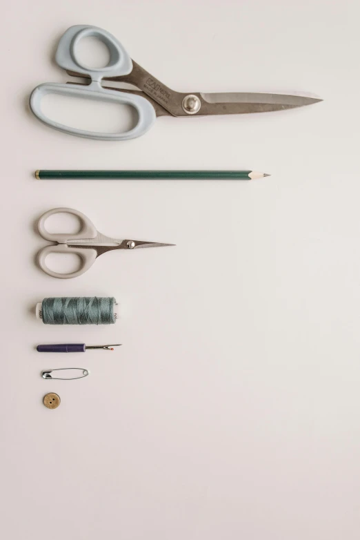 two pairs of scissors, two sewing needles and a stapler are sitting on a desk