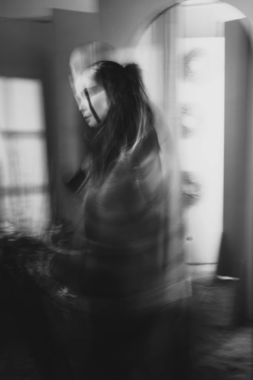 a woman sitting in front of a window with a blurry face