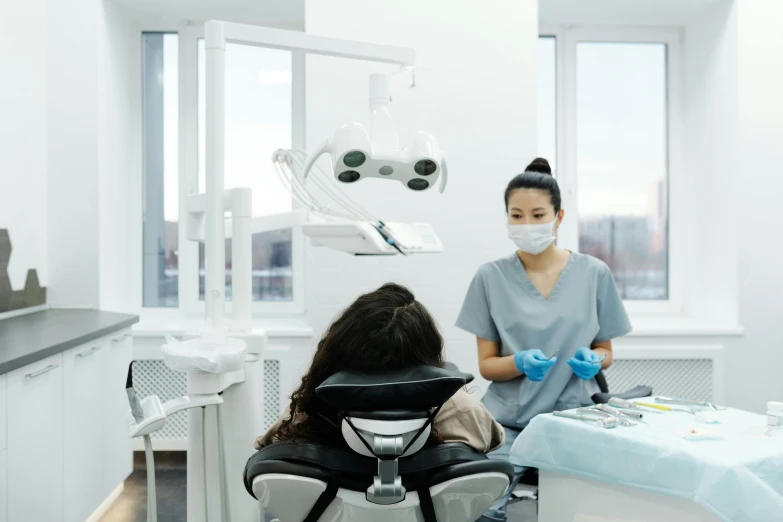 woman in a surgical setting sitting in chair wearing a face mask