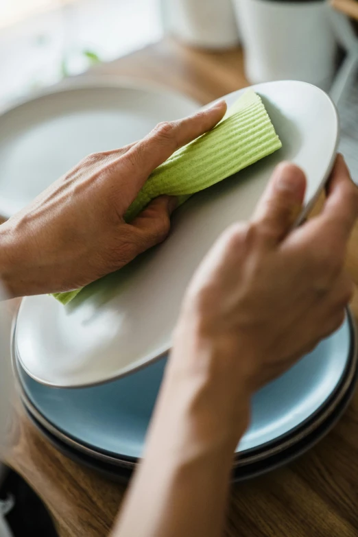 person cleaning a plate with a yellow cloth