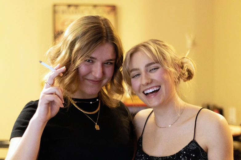 two girls pose for a picture and one has her nose pressed by the girl's finger