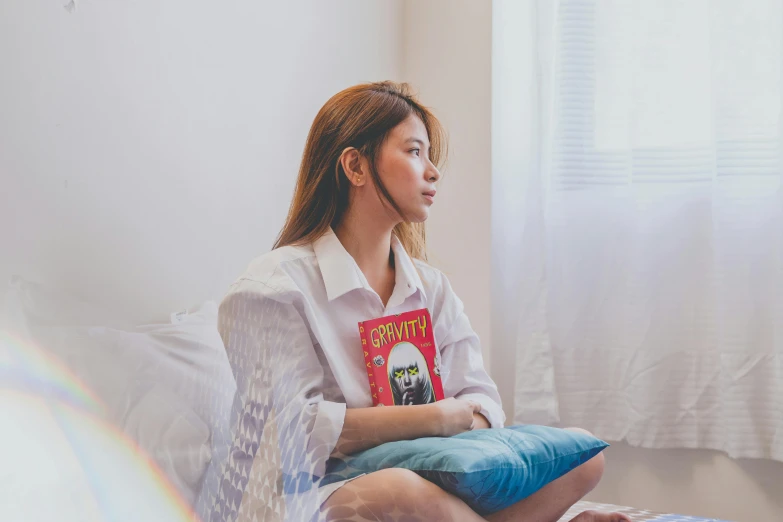 a woman is sitting on the bed reading a book