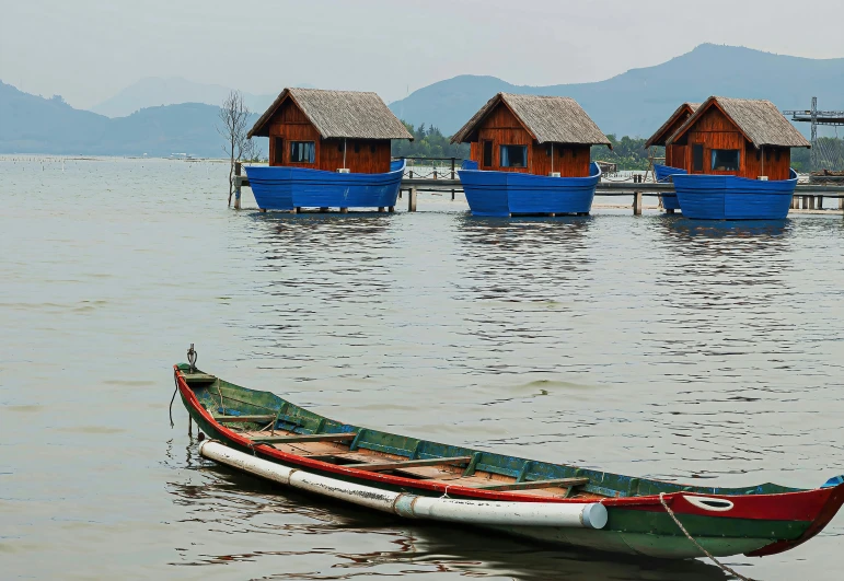 a rowboat is anchored by some floating huts