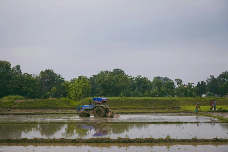 a man riding a tractor driving through a muddy field