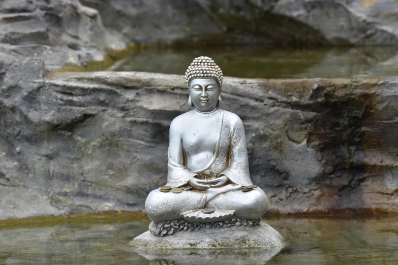 a small statue of a buddha sitting on a rock