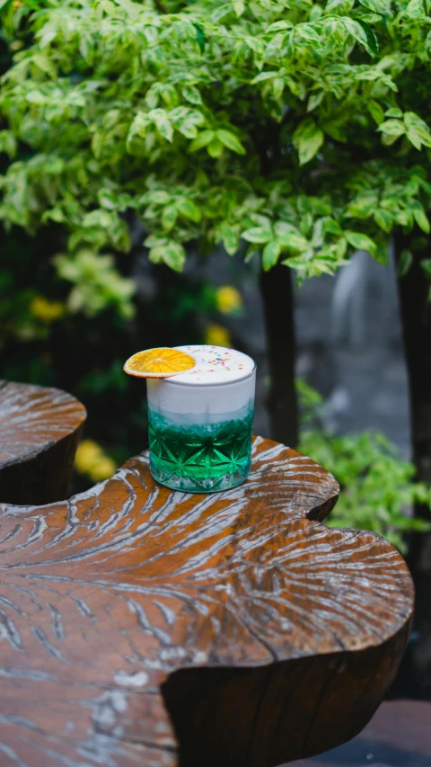 green and white cup with liquid on top on bench