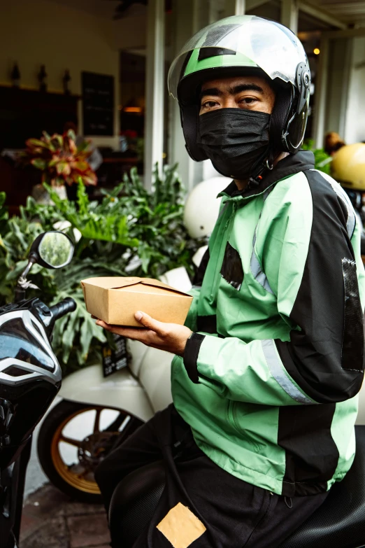 a man dressed in green and black sitting on a motorcycle