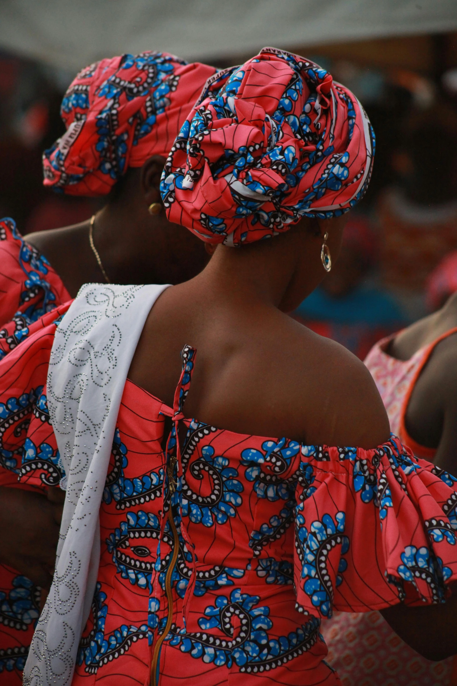 an african woman with red dress and flowered headdress in an audience