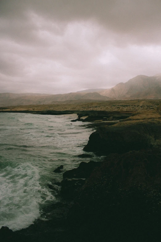 a rocky cliff edge with green water and brown grass