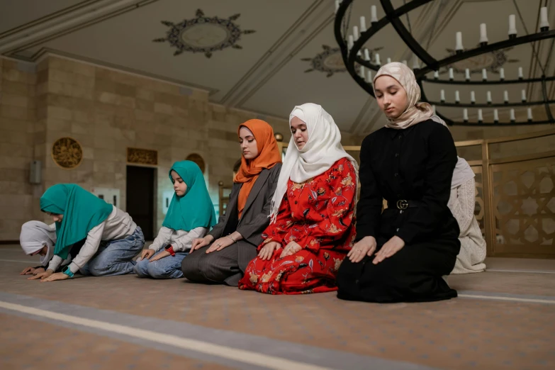 six women in hijab sit on the ground