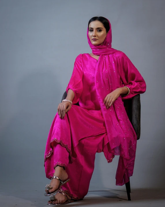 a woman wearing a pink dress sitting down