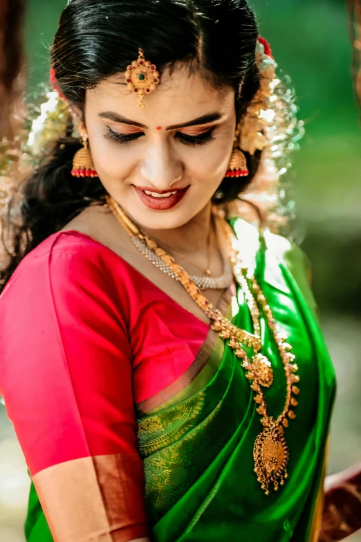 an indian woman in traditional dress is wearing gold jewelry