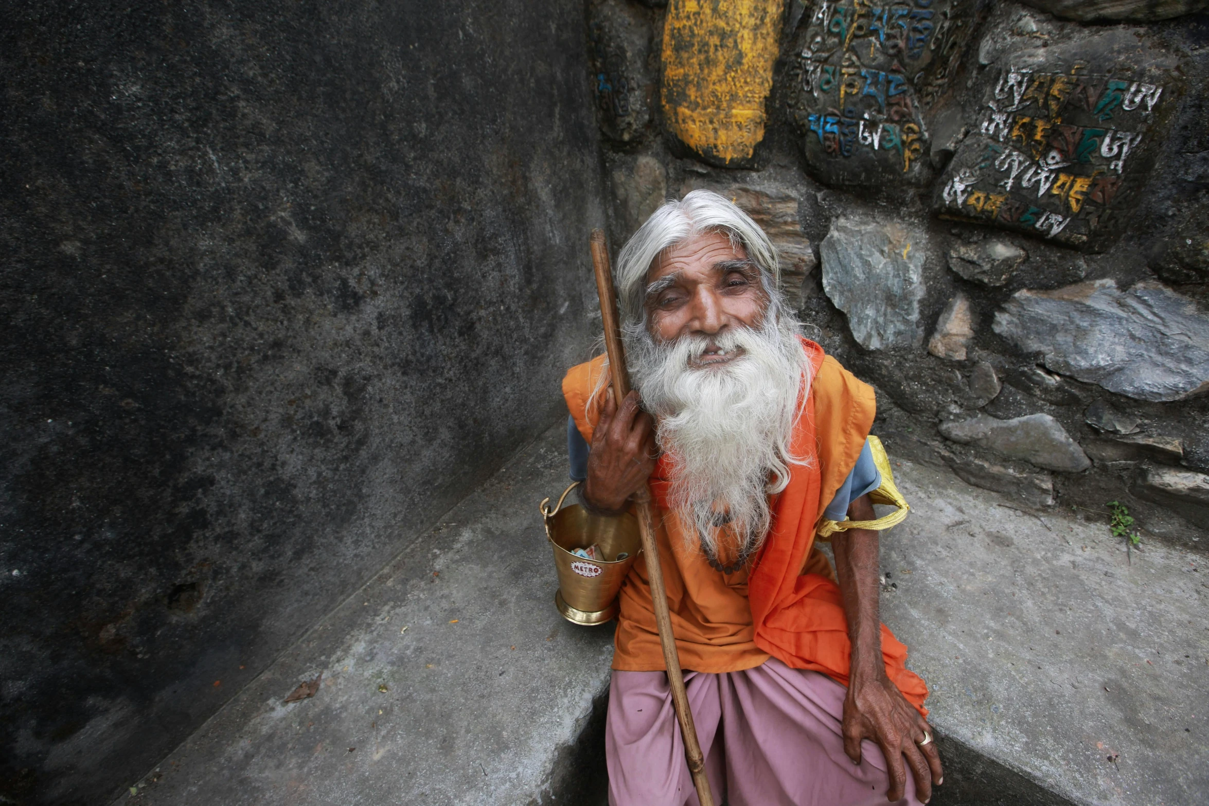 a old man in a orange robe is holding a stick