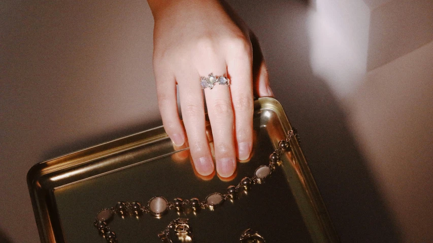 someone's hand holding onto a golden frame, with many necklaces