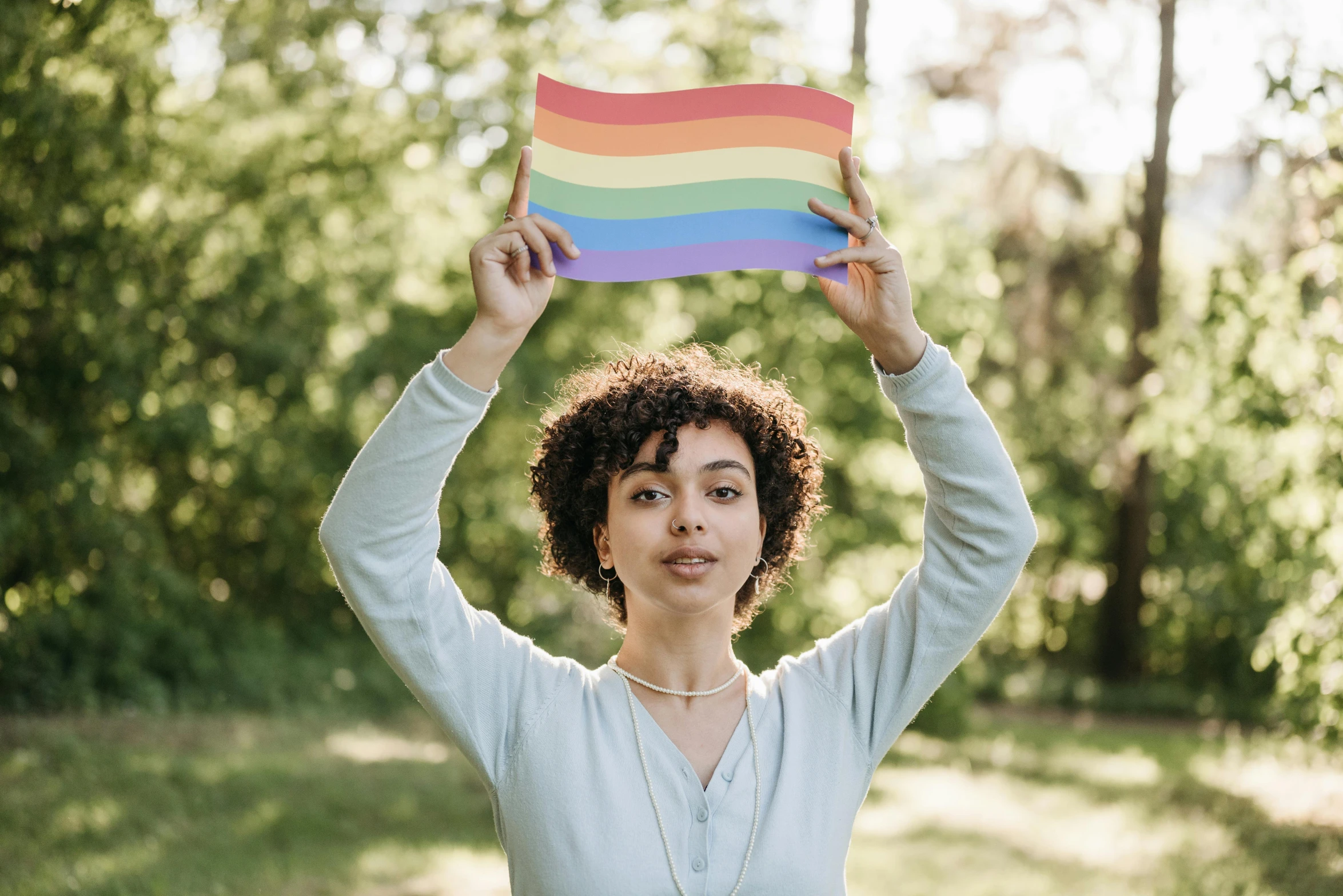 the woman is holding up a rainbow flag in her hands