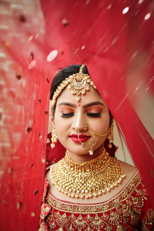 a woman in red with gold jewelry and a veil