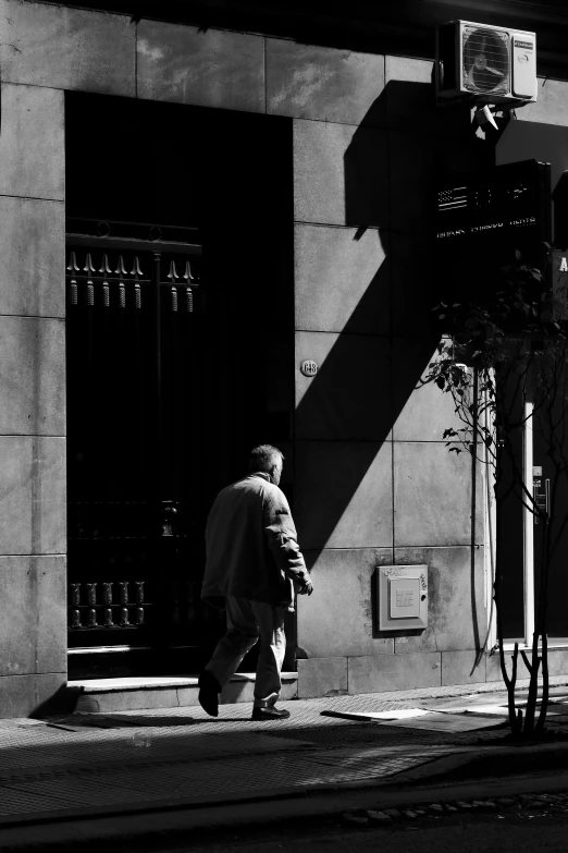 a black and white po of a person walking on the sidewalk