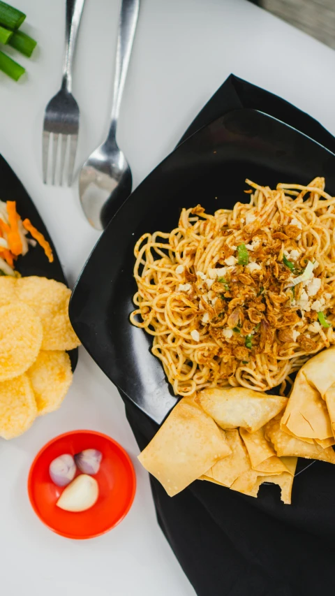 a plate of pasta, chips, and dip are shown