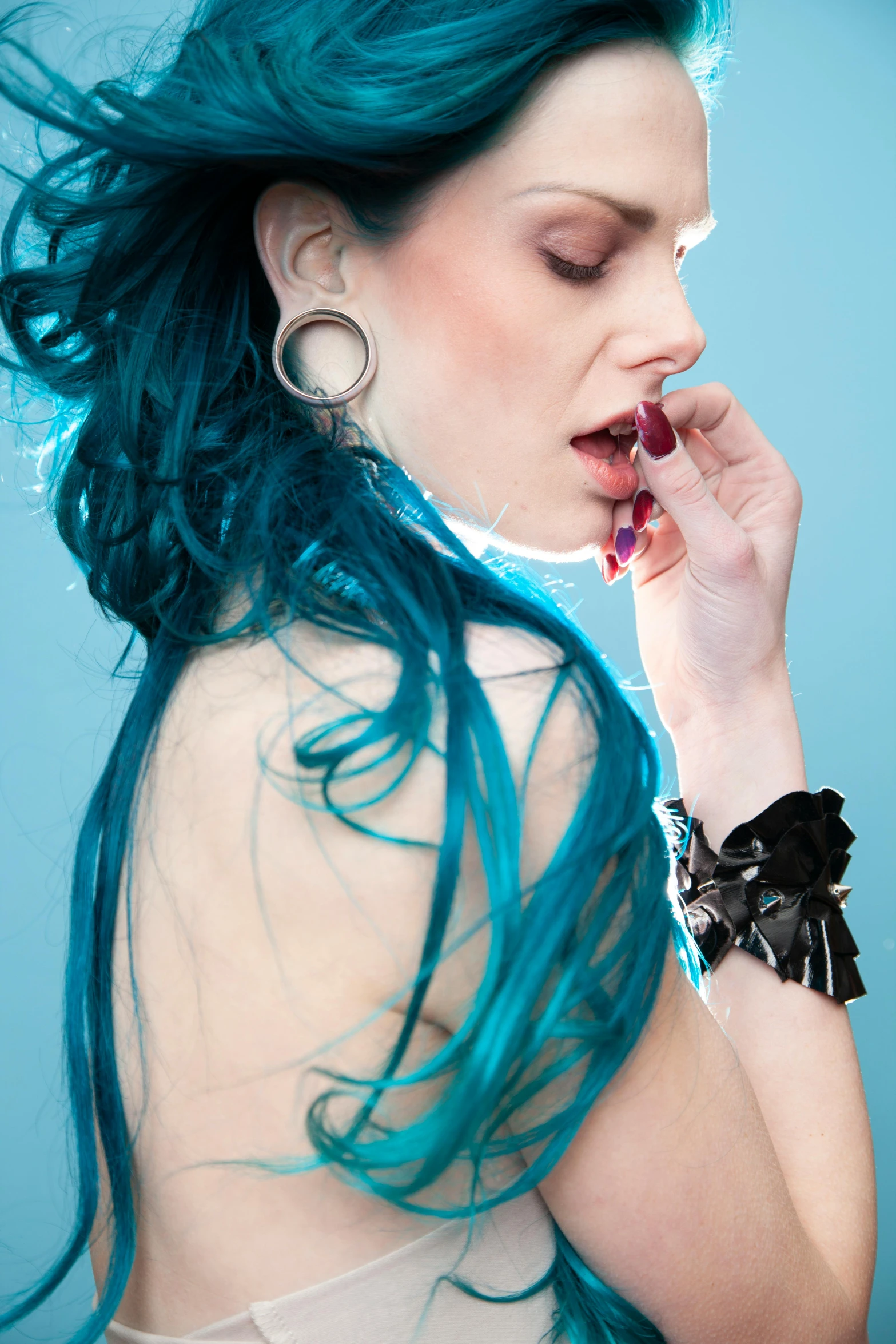 an attractive woman with blue hair wearing earrings and lipstick