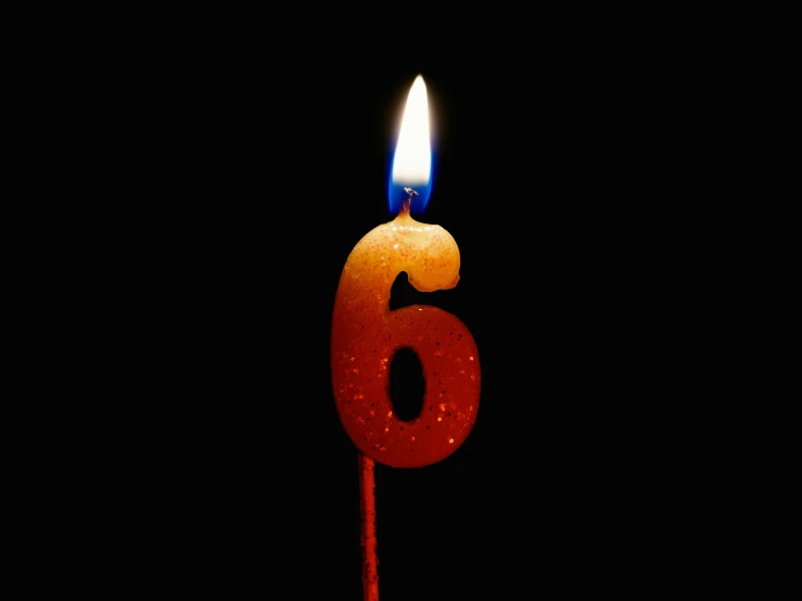 a burning candle with the number six in it