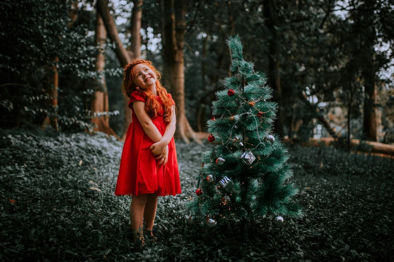 a red - headed woman is posing in front of a christmas tree