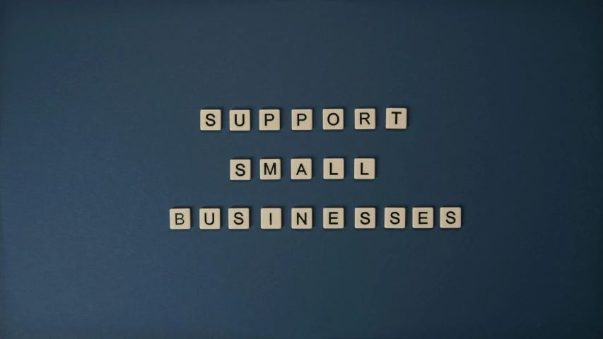 a sign with the words support small businesses spelled out in scrabble tiles