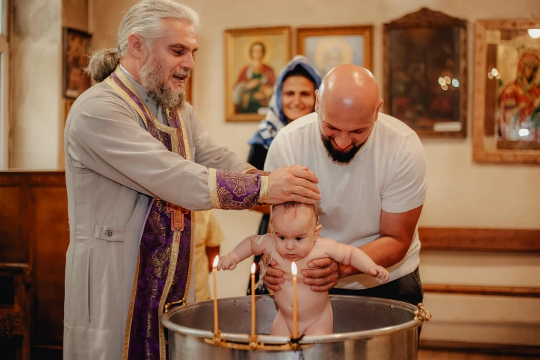 a couple of people washing a child in a large bucket