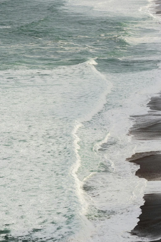 an ocean view with waves rolling in and people walking