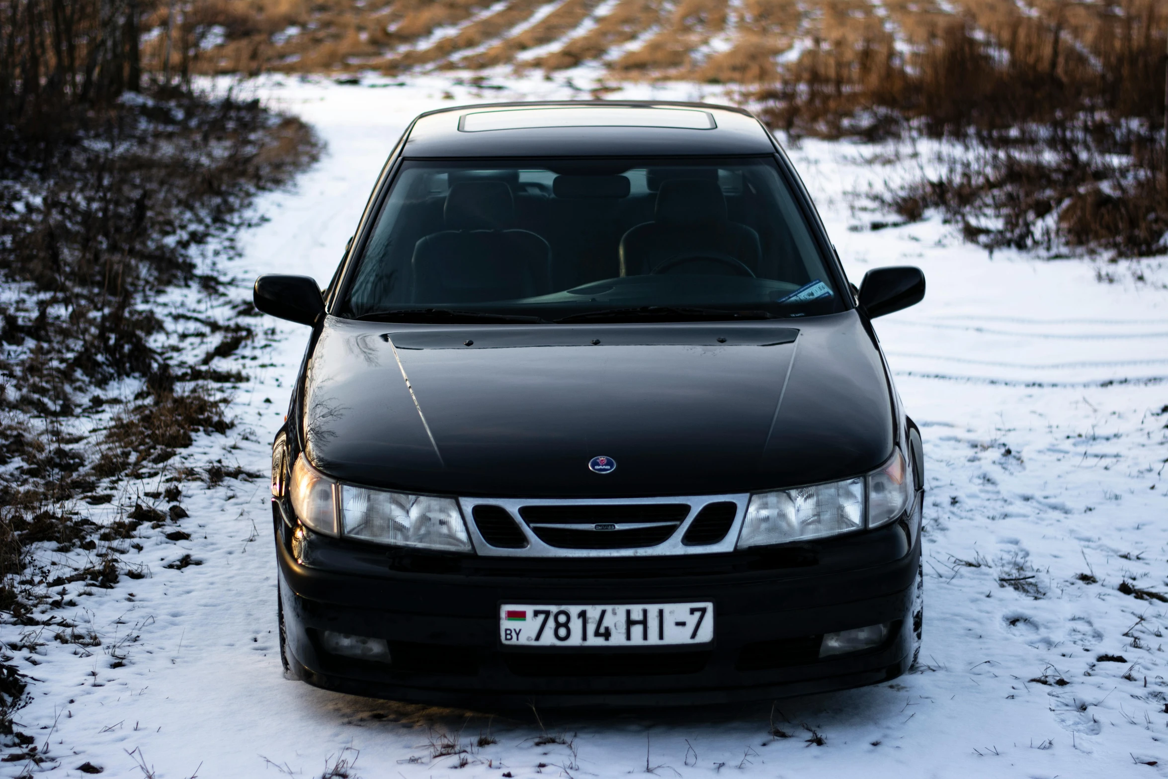 a black sedan parked on the side of a snow covered road