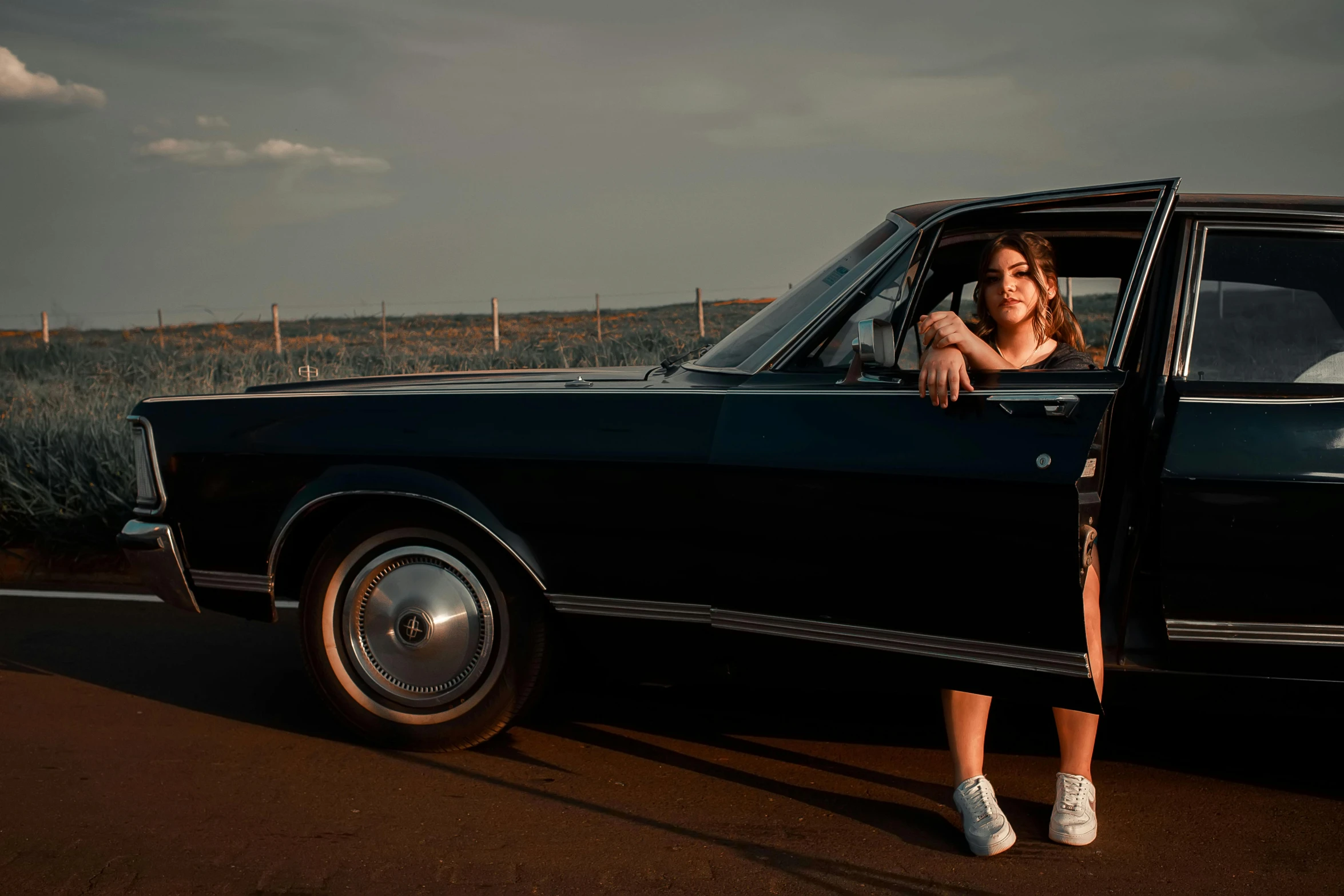 a woman in an old fashion car sits on the side