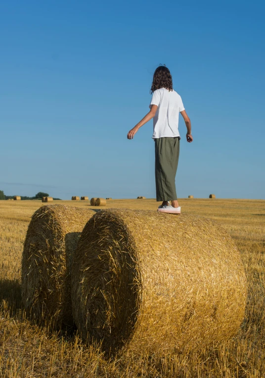 a girl standing on top of a bale of hay