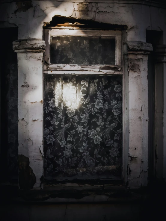 an old window and faded curtains in an abandoned building