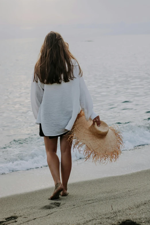 a woman is walking along the beach in her skirt