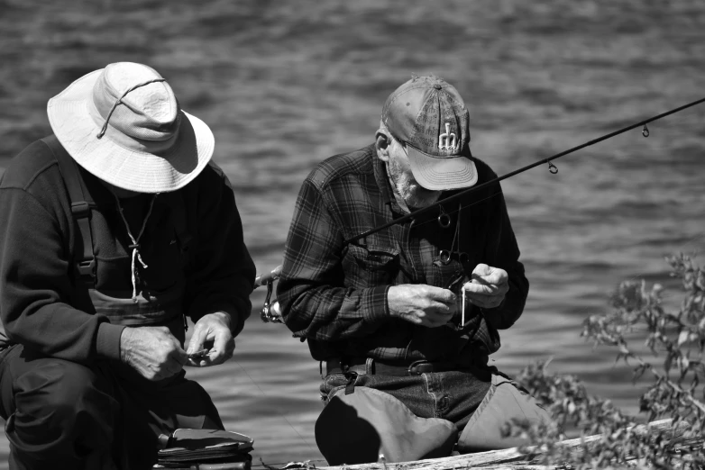 two men sitting and fishing in the water