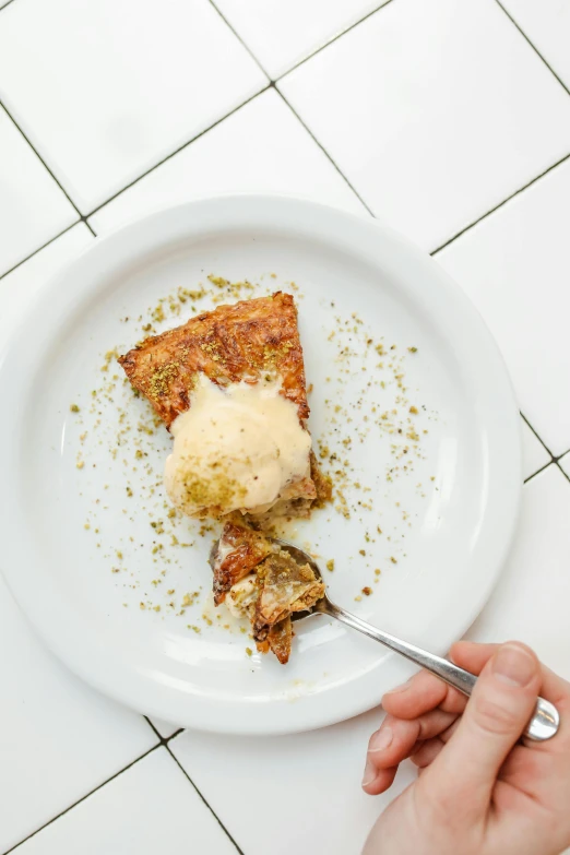 a hand holding a silver fork above some food