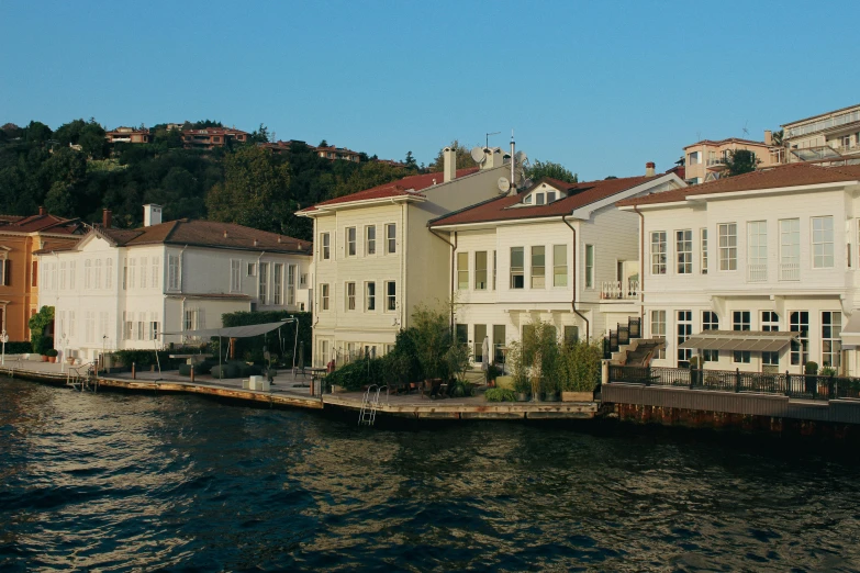 some white buildings water and trees on a hill