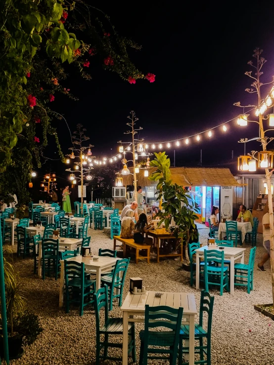 blue chairs sitting around tables and lights strung from above