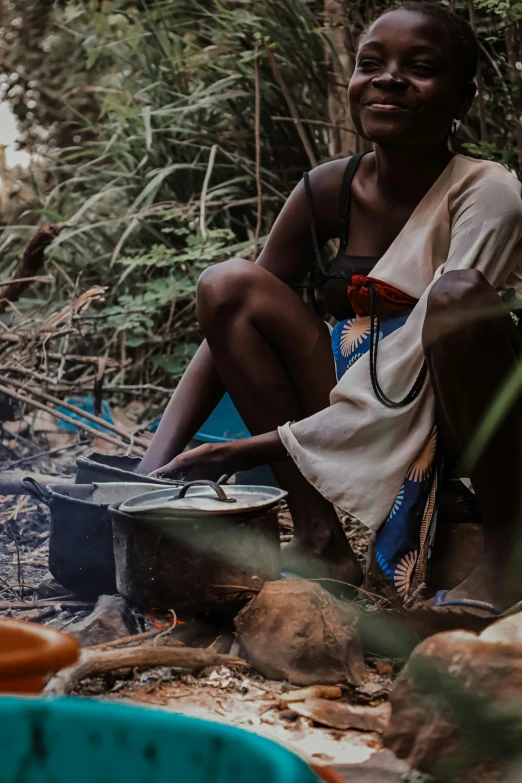 woman setting on campfire with stove, water and basket