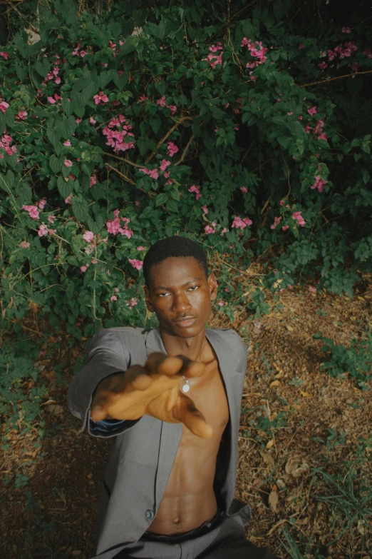 a man standing next to pink flowers holding soing