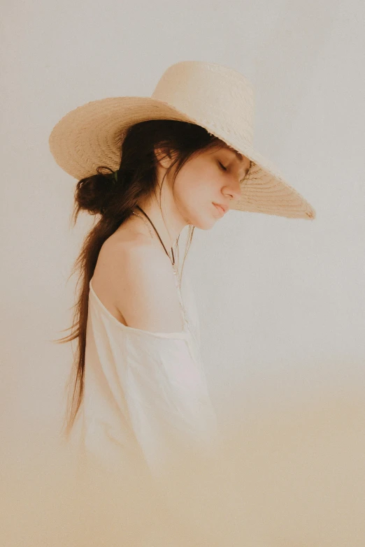 a woman with a floppy hat walks in the sand