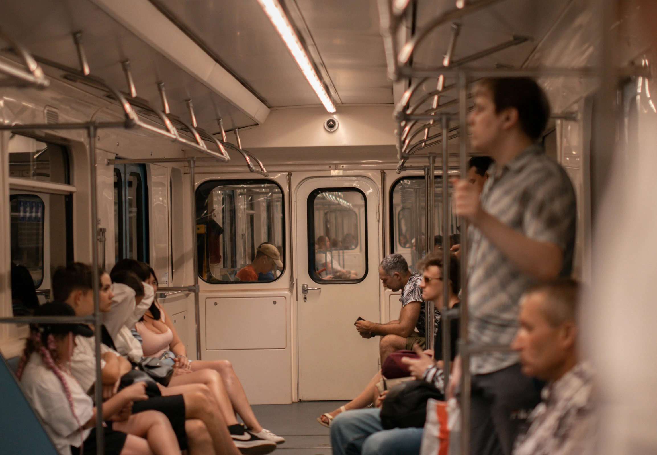 people sit and stand inside a passenger train