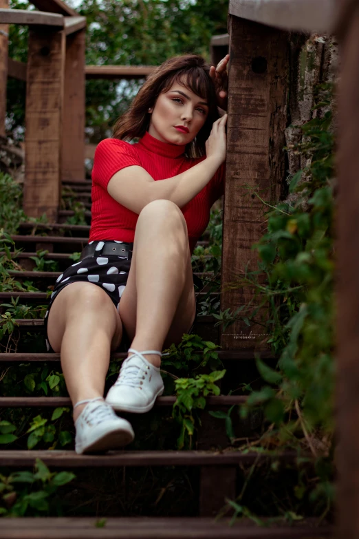 a woman in a red shirt sitting on a set of stairs