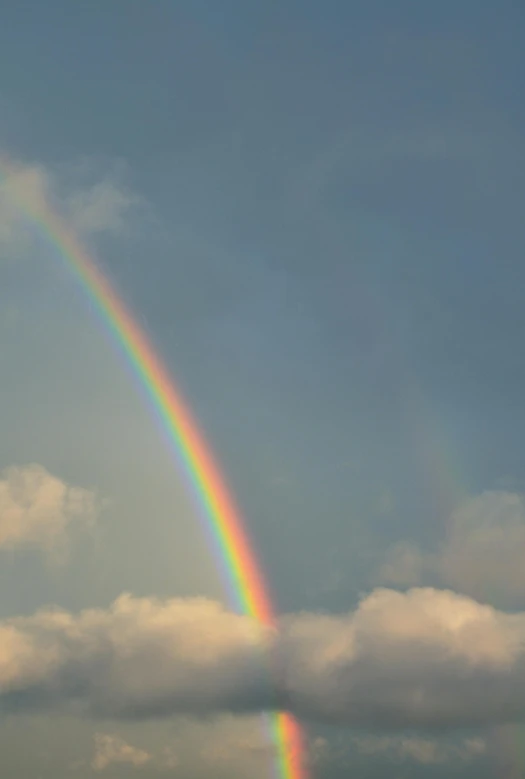 a rainbow appears in the sky as people are flying kites