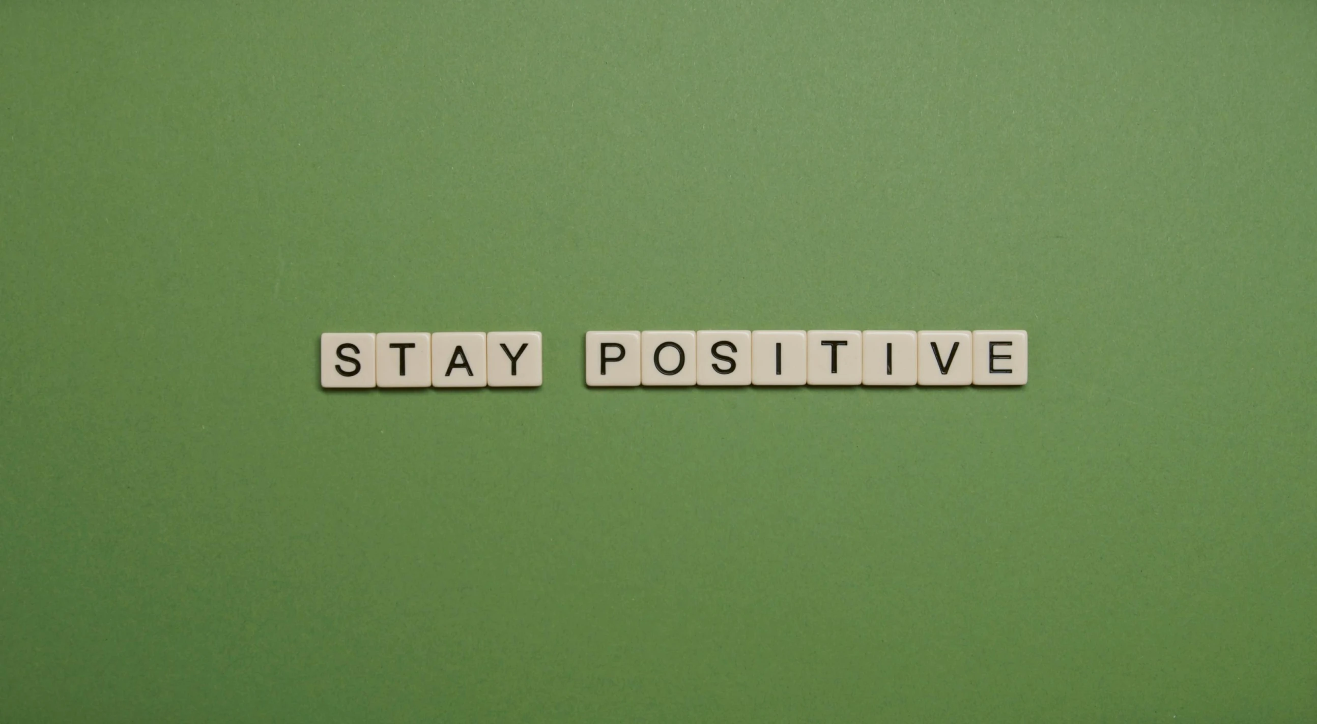 the word stay positive written on a green surface