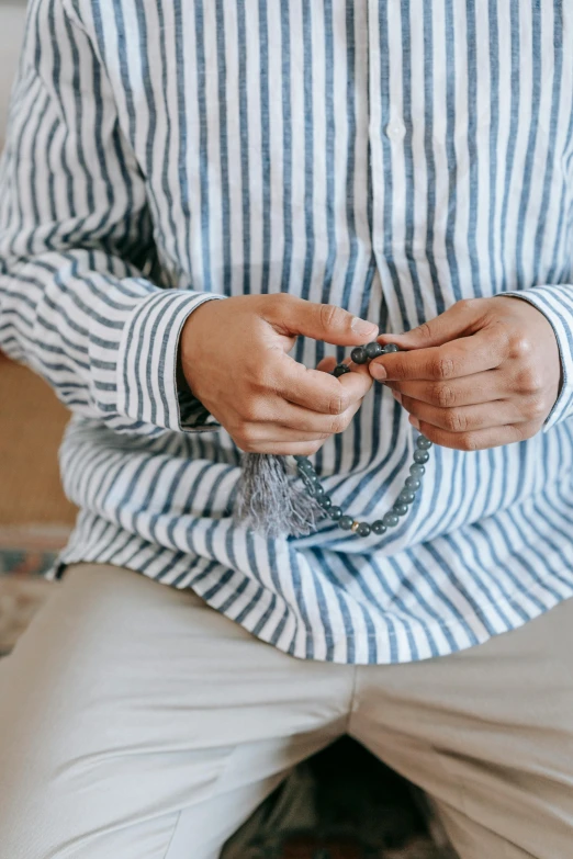 man wearing striped shirt sitting down with his hands holding a ring